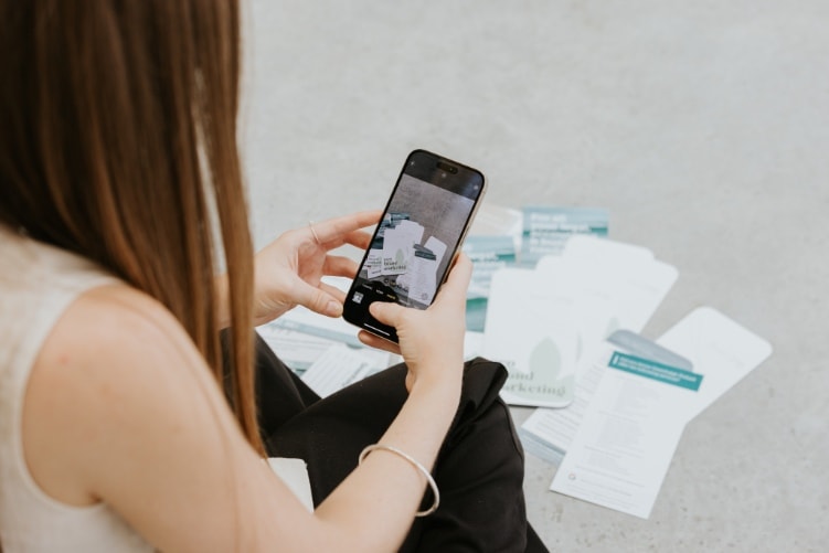 Person looking at a phone beside paperwork
